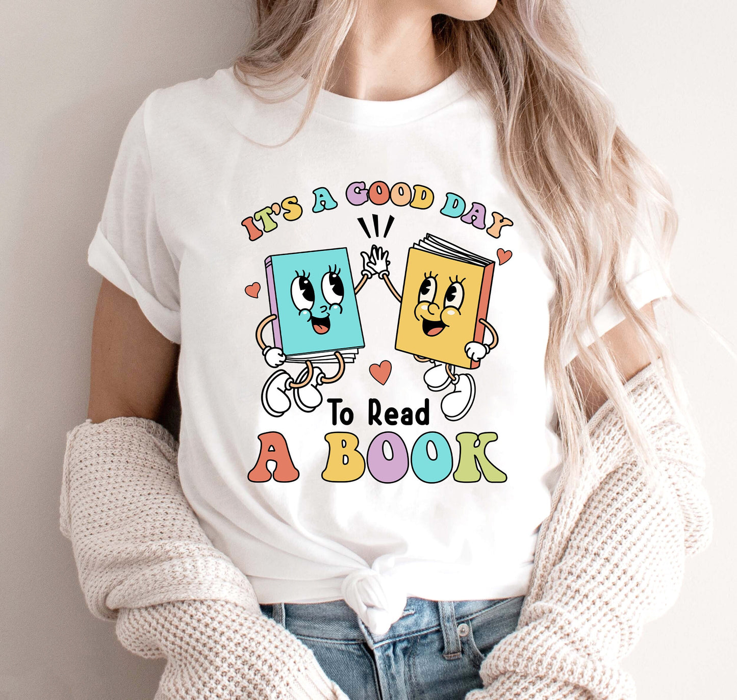 This whimsical image captures the essence of joy in reading, showcasing two books with charming smiles and dancing eyes, sharing a high-five, emphasizing the phrase IT&#39;S A GOOD DAY TO READ A BOOK, written in a casual, multicolored typeface.