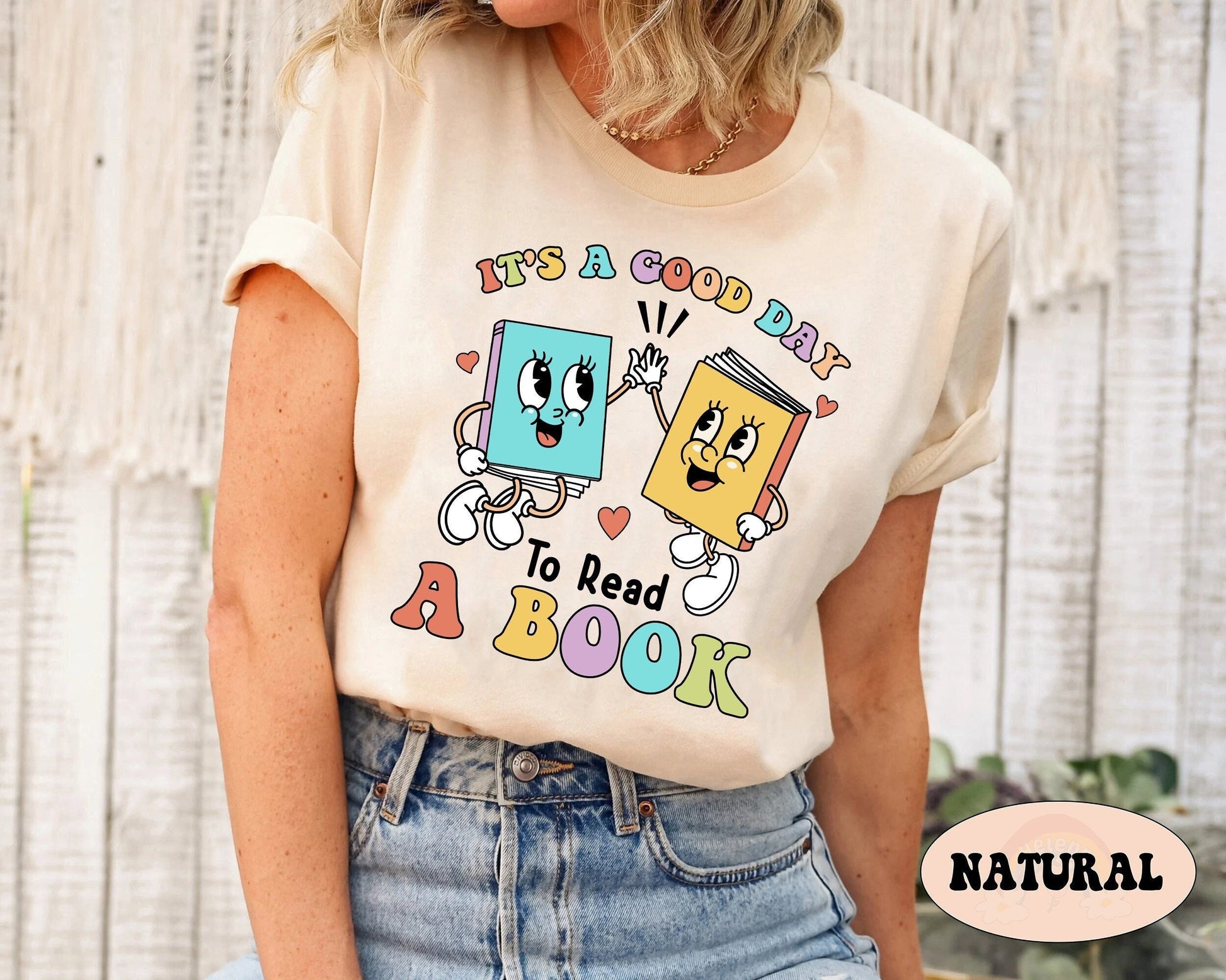 Two books with adorable facial features and animated hands connect in a high-five, symbolizing the fun and interactive nature of reading, with the motivational phrase IT&#39;S A GOOD DAY TO READ A BOOK arranged below in a spectrum of gentle hues.