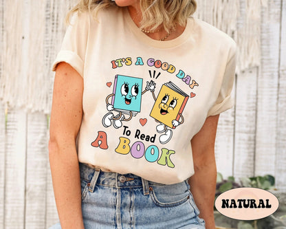 Two books with adorable facial features and animated hands connect in a high-five, symbolizing the fun and interactive nature of reading, with the motivational phrase IT&#39;S A GOOD DAY TO READ A BOOK arranged below in a spectrum of gentle hues.