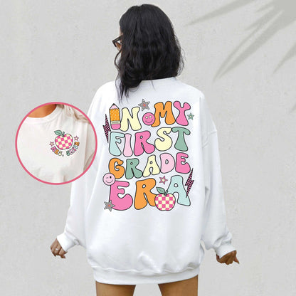 An energetic graphic with the phrase In my first grade era displayed in bold colorful letters The design includes playful symbols like a pencil apple stars and smiley faces adding a lively and positive touch