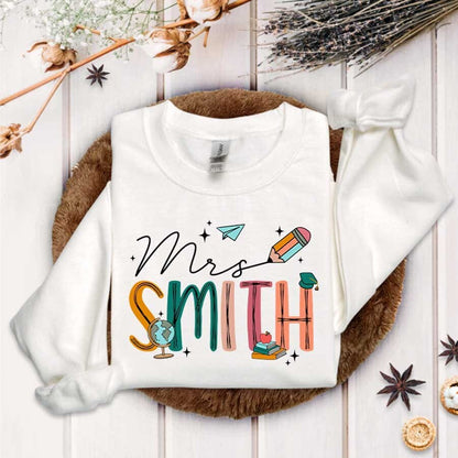 A bright design for Mrs. Smith where each letter is crafted from educational items like a globe, pencil, and books accented with a paper airplane and graduation cap.