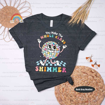 The illustration showcases a disco ball personified with lively facial features, flanked by the phrase WHOLE CLASS SHIMMER in playful colors, reflecting the dazzling effect of a cohesive and joyful classroom.