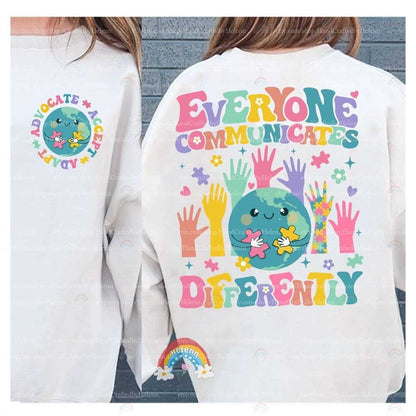 The illustration encapsulates the beauty of diverse interactions with a central globe character piecing together puzzles, encircled by a variety of vibrant hands reaching in, all beneath the guiding words EVERYONE COMMUNICATES DIFFERENTLY