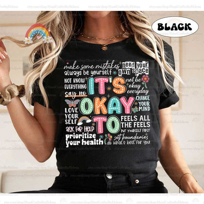 The playful design spells out It&#39;s Okay To with each letter dotted in vibrant shades, mingled with symbols of hope and change, including a rainbow and butterfly, reinforcing the notion that it’s alright to ask for help and embrace change.