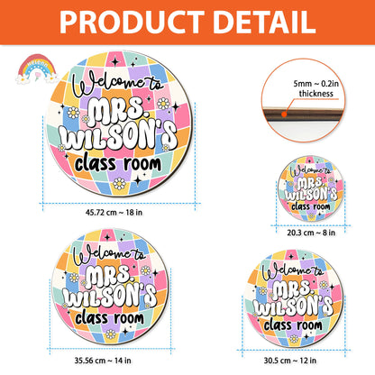 Cheerful greeting sign hanging on a classroom door with the words Welcome to Mrs. Wilson’s classroom, adorned with a colorful and festive design including flowers and stars.