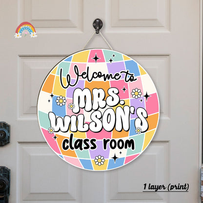Circular classroom welcome sign for Mrs. Wilson featuring a colorful patchwork design with stars, flowers, and vibrant lettering on a door background.