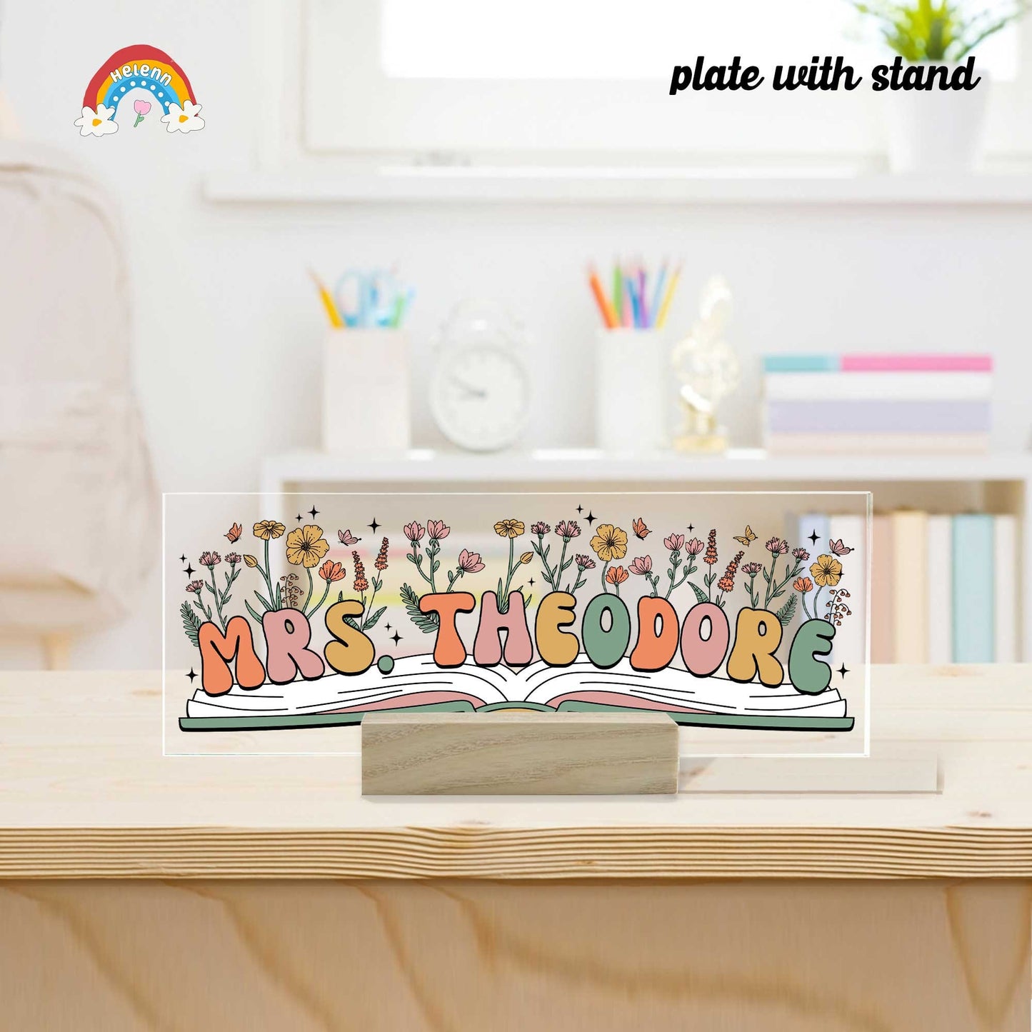 An artistic nameplate that includes the name Mrs. Theodore, set on a rich wooden stand, decorated with a variety of colorful flowers, adding a personal and welcoming touch to her teaching space.