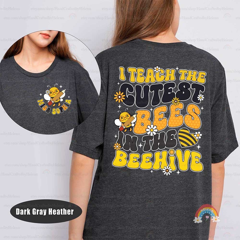 An endearing teacher’s graphic showcasing the phrase I Teach the Cutest Bees in the Beehive in yellow, with a playful bee and whimsical floral designs on a black background.