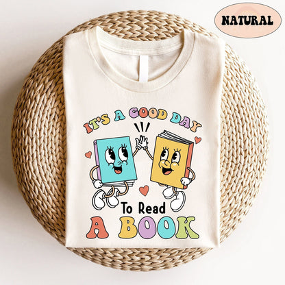 The joyful scene depicts two anthropomorphic books, each with lively expressions and cartoonish limbs, high-fiving over the encouraging words IT&#39;S A GOOD DAY TO READ A BOOK displayed in a playful font with an array of pastel colors.