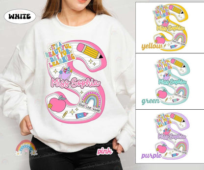 An attractive layout with the name set against a backdrop of school-themed illustrations including a rainbow and stars, perfect for a teacher with a lively personality.