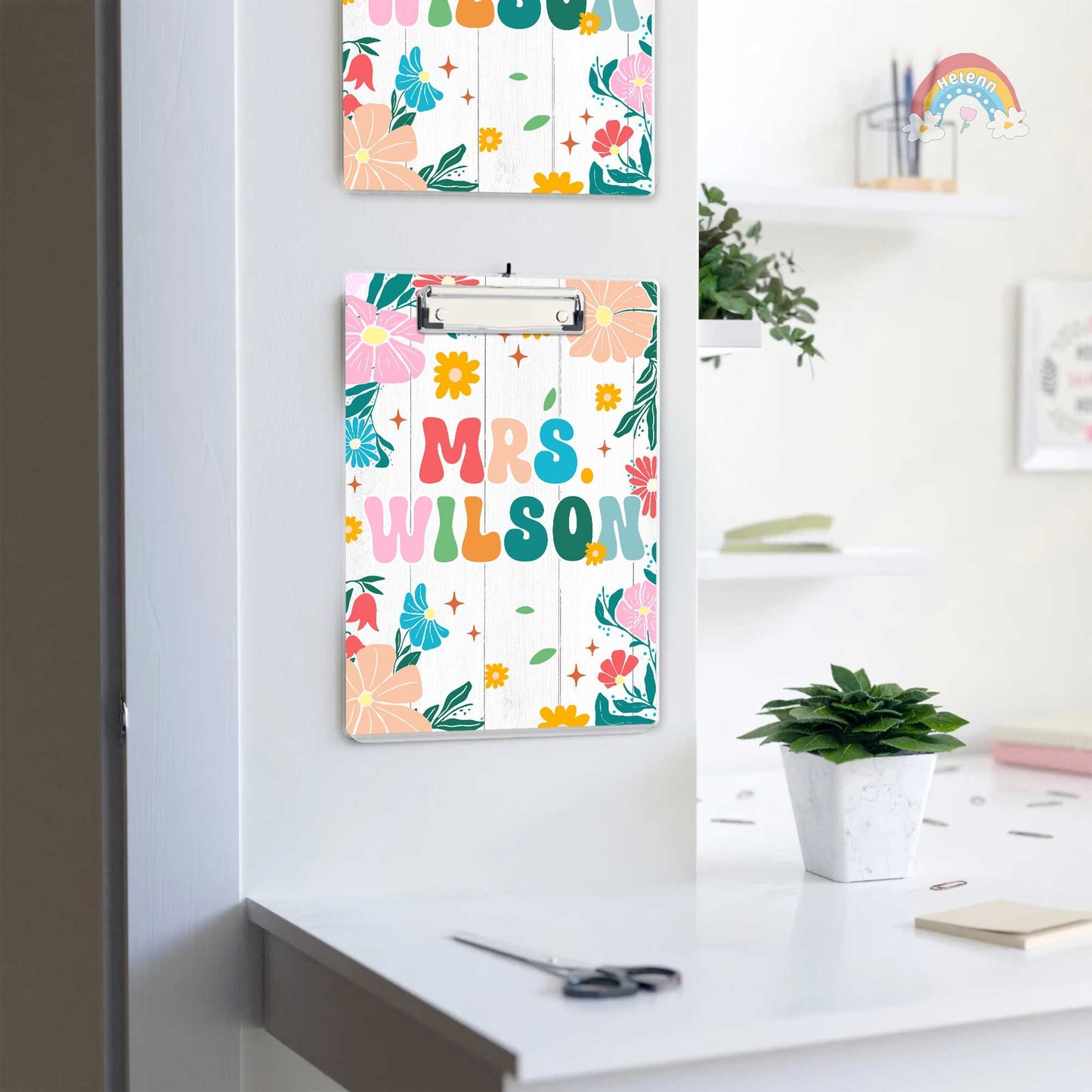 The clipboard showcases a personalized touch with Mrs. Wilson written in colorful, bold letters surrounded by a variety of bright flowers.