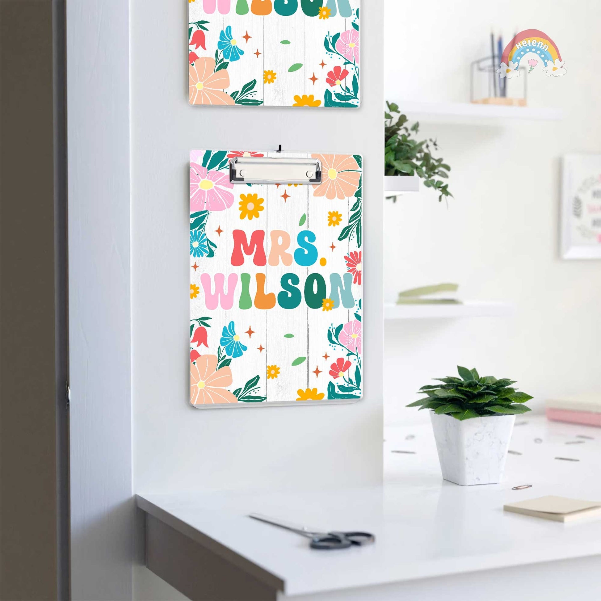 The clipboard showcases a personalized touch with Mrs. Wilson written in colorful, bold letters surrounded by a variety of bright flowers.