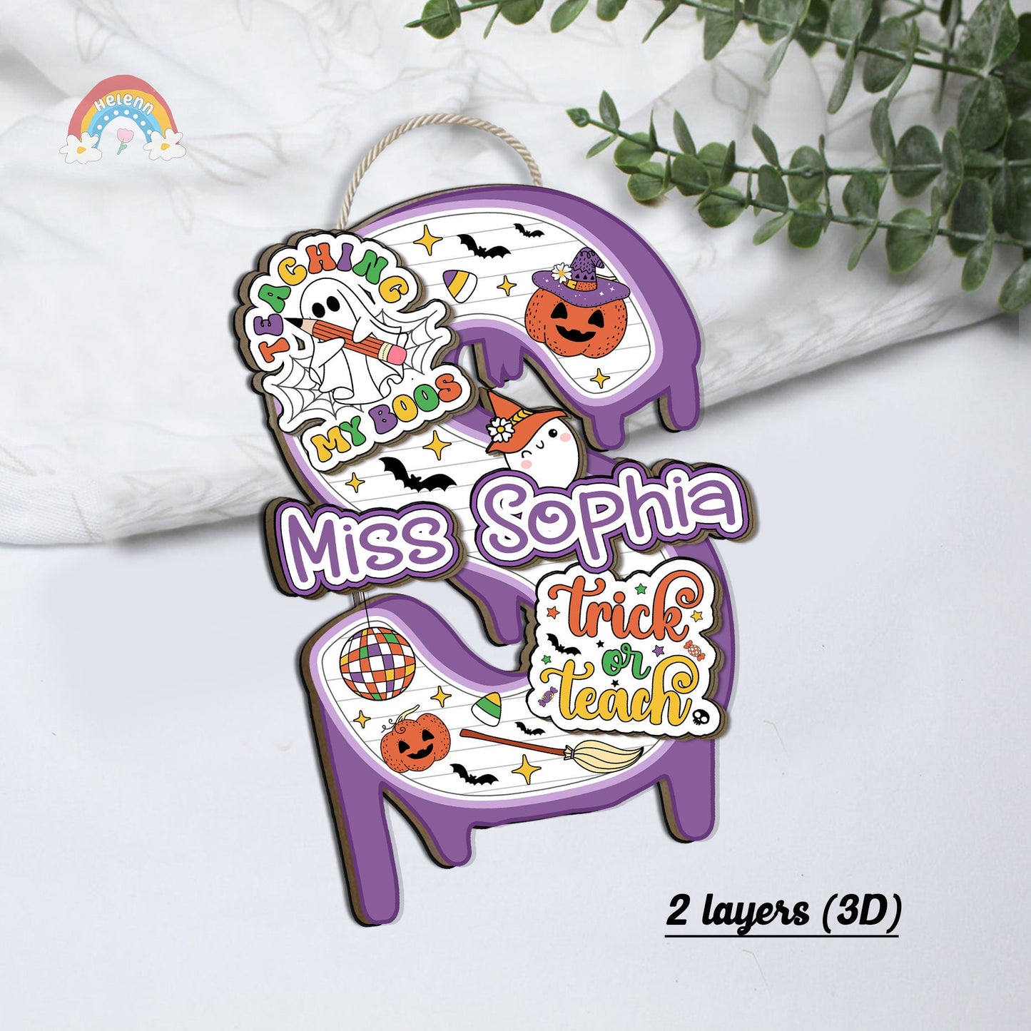 The design includes a cute ghost with the phrase Teaching My Boos and Halloween icons like witches&#39; hats and brooms, making it a festive addition to any classroom door.