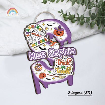 The design includes a cute ghost with the phrase Teaching My Boos and Halloween icons like witches&#39; hats and brooms, making it a festive addition to any classroom door.