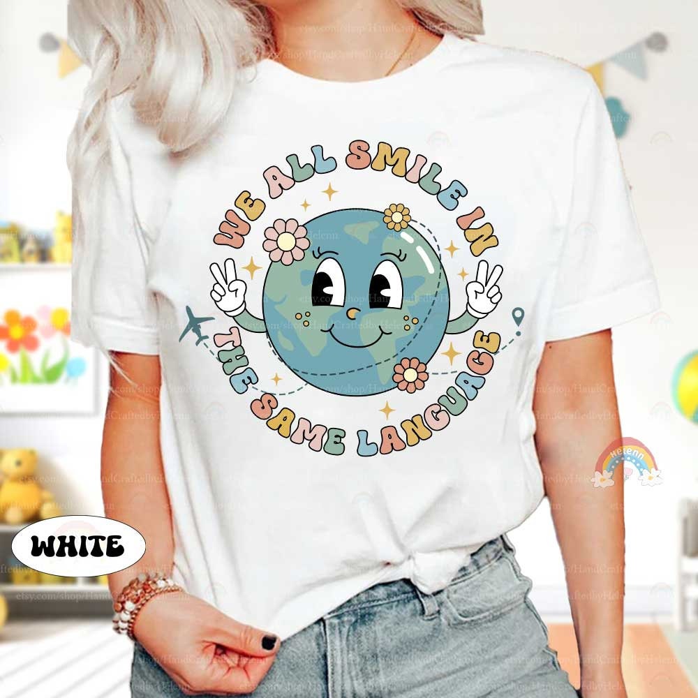 A playful graphic with the words We all smile in the same language encircling a happy globe character The design includes cute details like flowers and an airplane symbolizing global connection and harmony