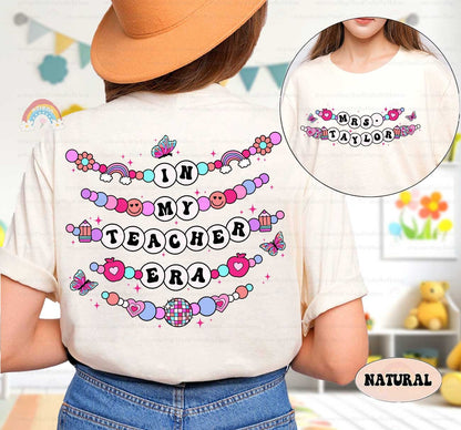 A vibrant graphic displaying In My Educator Era in beaded-style letters, surrounded by whimsical elements like smiley faces, apples, and a disco ball, all on a pink backdrop.