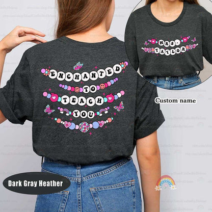Delightful and colorful, this T-shirt design features the phrase Enchanted to Teach You, surrounded by beaded elements, butterflies, and hearts. The custom name on the front adds a charming and personal touch to this enchanting theme.