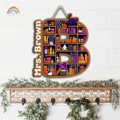 Playful and spooky Halloween door hanger featuring a large letter B decorated with pumpkins, ghosts, and Halloween-themed books. The name Mrs. Brown adds a unique, personalized element.
