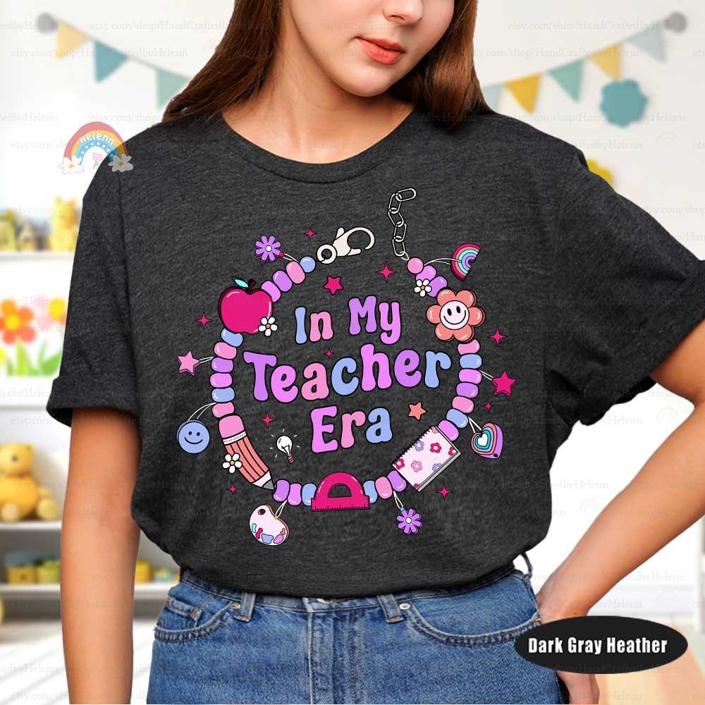 Fun and stylish T-shirt design featuring In My Teacher Era, creatively encircled by a beaded bracelet with charming details like apples, pencils, and smiley faces. A great way to express teacher pride.