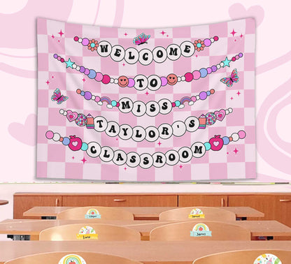 A playful classroom banner displaying Welcome to Miss Taylor&#39;s Classroom in beaded-style letters with butterflies, hearts, and stars on a pink checkered backdrop.