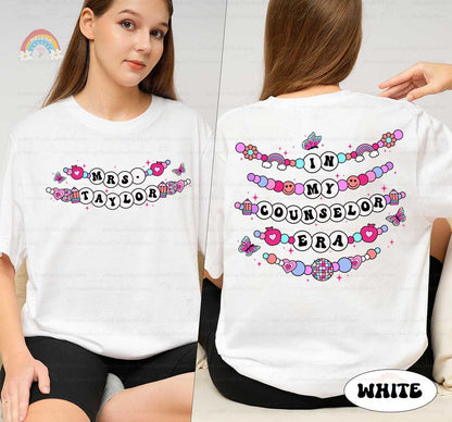 A whimsical graphic with In My Educator Era in bold beaded-style letters, surrounded by colorful elements like rainbows, hearts, and butterflies, set on a pink background for a joyful theme.