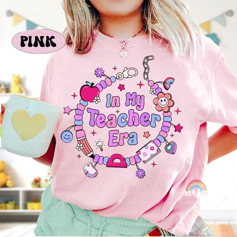 Whimsical T-shirt with the phrase In My Teacher Era, surrounded by a colorful beaded bracelet filled with cheerful charms. The design captures the joy and pride of being in the teaching profession.