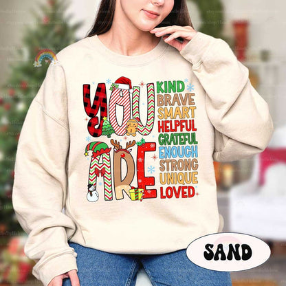 Uplifting holiday-themed T-shirt with bold, decorative letters spelling You Are, followed by empowering words like Unique, Enough, and Loved. A perfect way to spread kindness and holiday spirit.