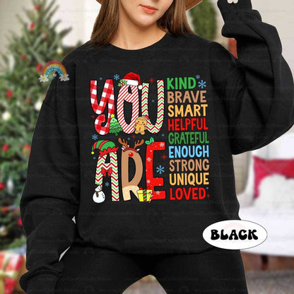 Whimsical design filled with festive patterns and affirmations such as Smart, Kind, and Brave. This cheerful T-shirt delivers a positive message while adding holiday fun.