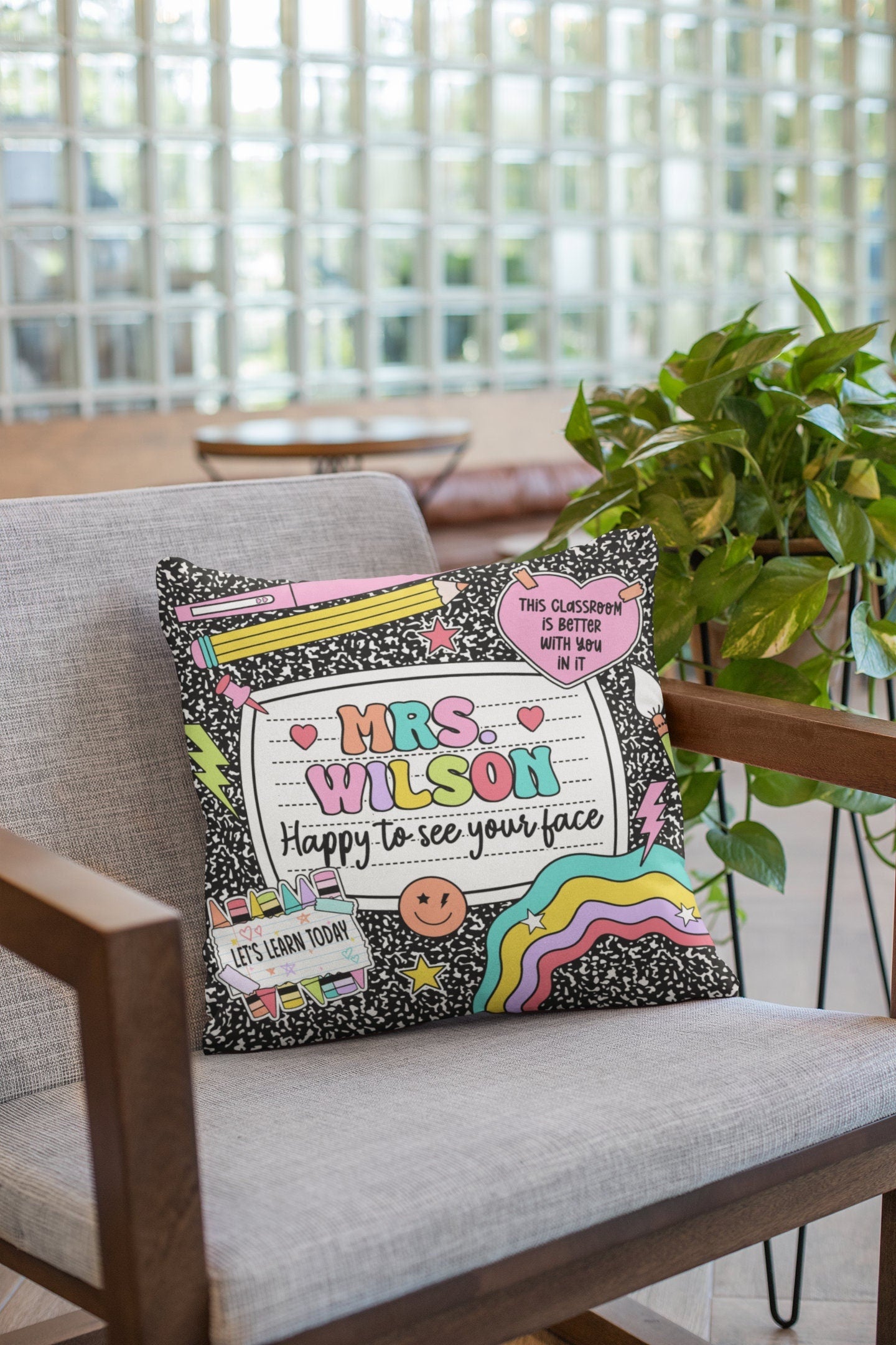 Cheerful and playful pillow design with name and a positive message, surrounded by fun school-themed illustrations like pencils and notebooks. The bright colors and classroom accents make it perfect for adding some joy to a teacher’s room.
