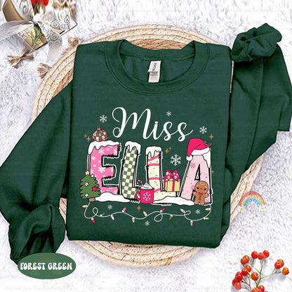 Whimsical and colorful design with the name Miss Ella surrounded by holiday symbols like a Christmas tree, presents, and a gingerbread man. A great way to bring festive spirit to the classroom.