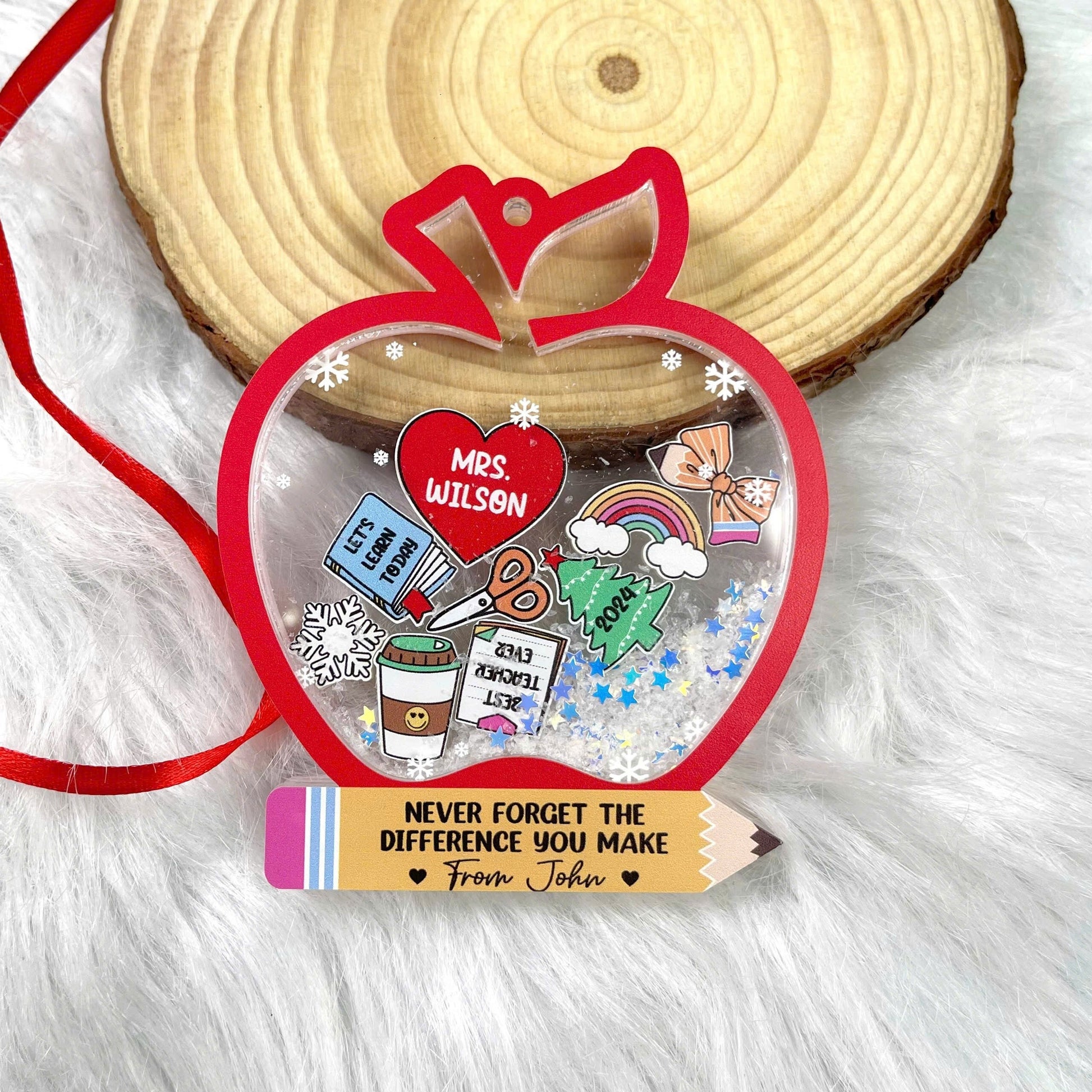 Bright and fun teacher ornament in the shape of an apple, decorated with icons and a personalized heart for Mrs. Wilson. The shakeable snow and touching message from John make it a perfect gift for celebrating a special teacher.