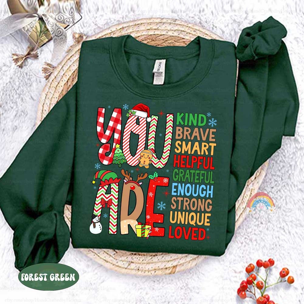 Fun and colorful T-shirt featuring decorated letters and a list of affirmations that remind everyone they are Grateful, Brave, and Loved, adding a special touch to the holiday season.