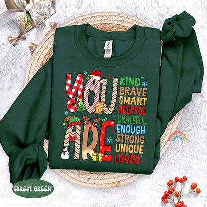 Fun and colorful T-shirt featuring decorated letters and a list of affirmations that remind everyone they are Grateful, Brave, and Loved, adding a special touch to the holiday season.