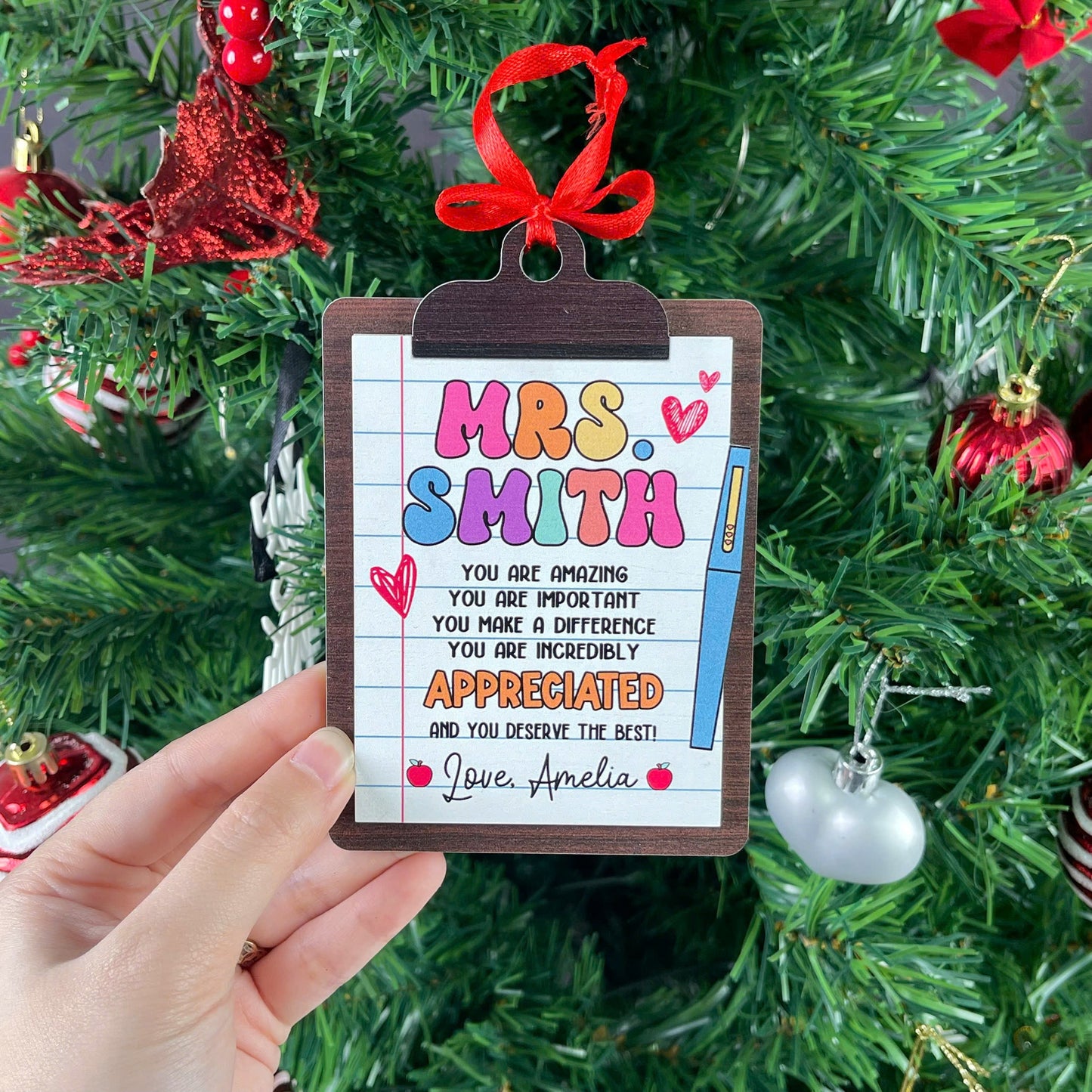 Whimsical ornament designed like a notebook page on a clipboard, expressing gratitude for Mrs. Smith. The message emphasizes how appreciated and important she is, with a personal touch from Love, Amelia.