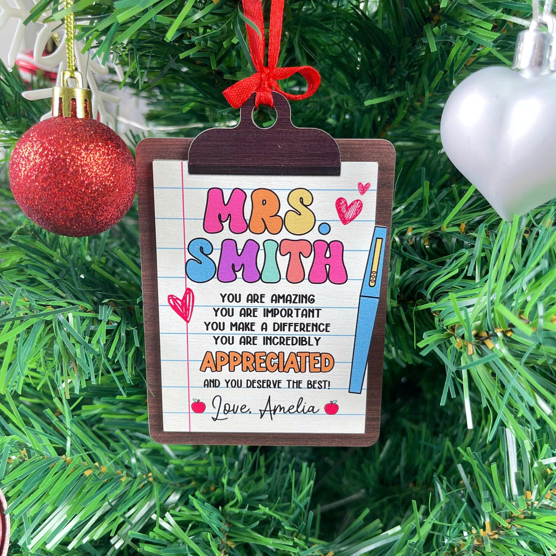 Festive ornament shaped like a clipboard, personalized with Mrs. Smith’s name and a message highlighting how important and appreciated she is. The personal touch from Love, Amelia makes it a meaningful keepsake.