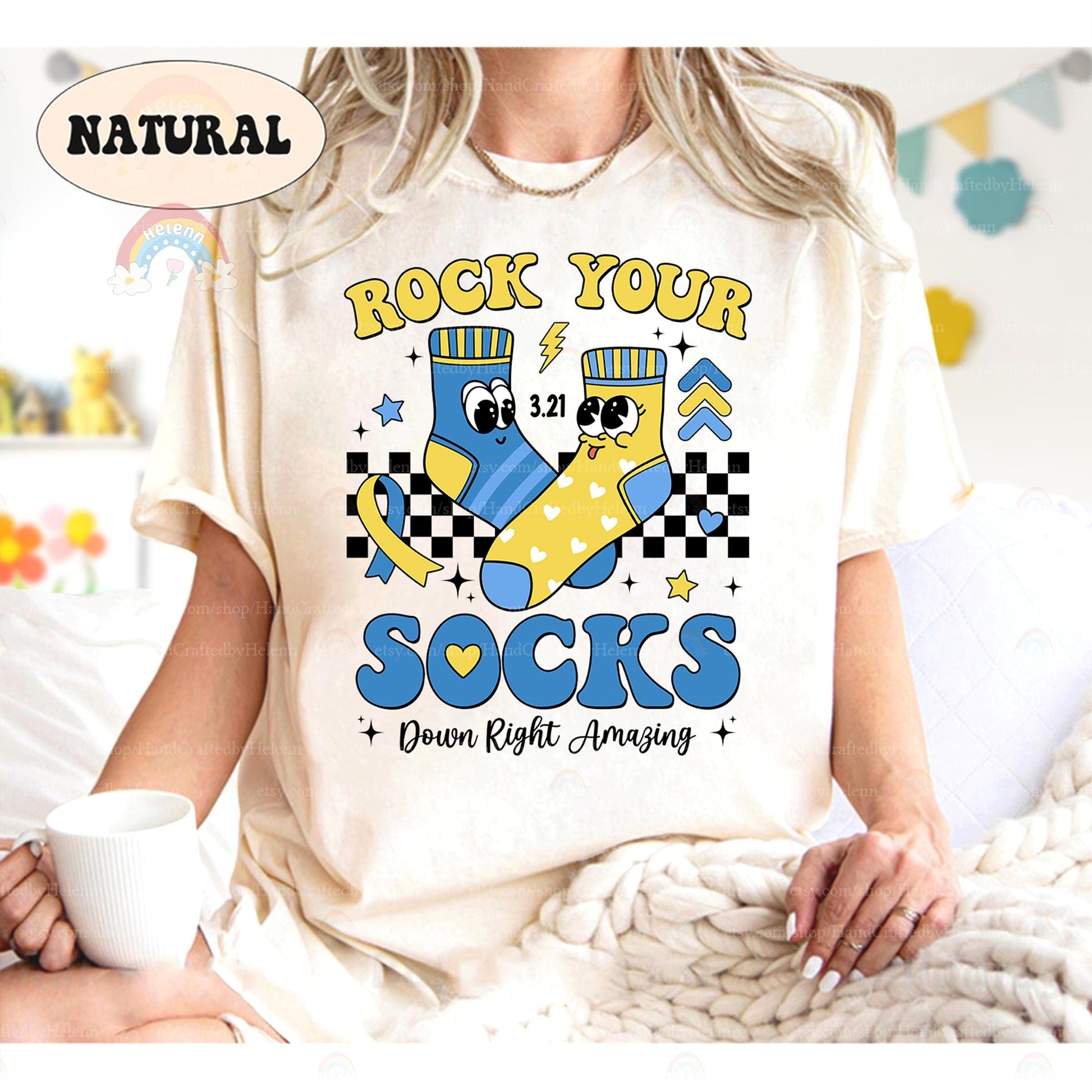 Celebrate uniqueness with this natural T-shirt featuring playful blue and yellow socks, checkered patterns, and 3.21. The bold &quot;Rock Your Socks&quot; message and &quot;Down Right Amazing&quot; slogan make it perfect for spreading positivity and awareness.