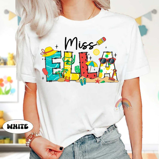 May include: White t-shirt with a colorful graphic design that says &#39;Miss Ella&#39; with beach-themed illustrations including a watermelon, sunglasses, a beach umbrella, a starfish, and a shovel.